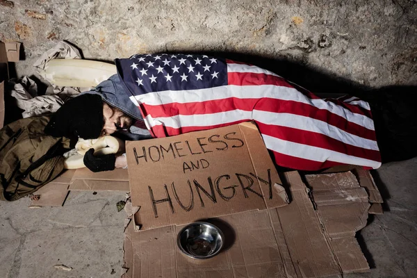 Man with alms bowl sleeping under American flag — Stock Photo, Image