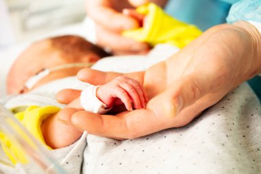 Yoğun bakım ünitesinde bir annenin elinin ve prematüre doğan bebek çocuğunun yakından izlenmesi