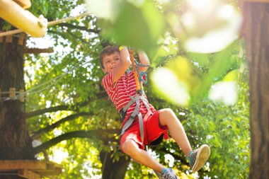 Bir ağaç platformundan anther'e teleferik çizgisinden aşağı kayan bir çocuğun portresi