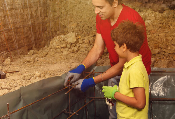Father and son doing small house basement construction work preparing framework for concrete pouring