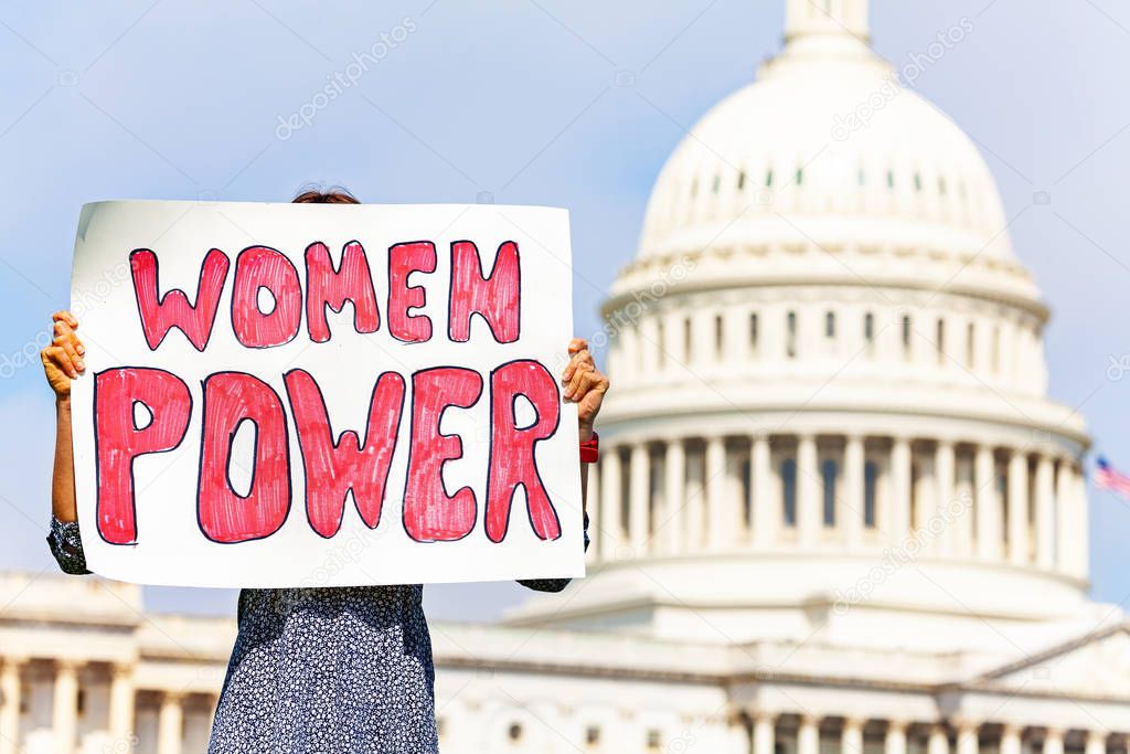 Woman protest in front of the USA capitol in Washington holding sign saying  women power