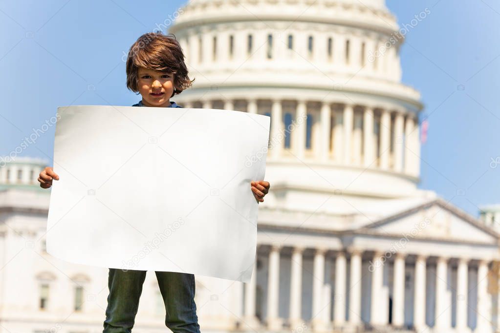 Child boy protest in front of the USA capitol in Washington holding empty sight banner with copy-space