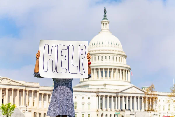 Woman protest in front of the USA capitol in Washington holding sign saying Help in her hands