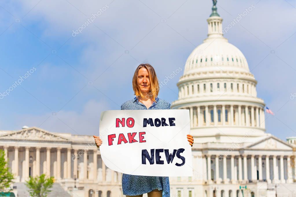Woman protest in front of the USA capitol in Washington holding sign saying no more fake news protesting against propaganda 