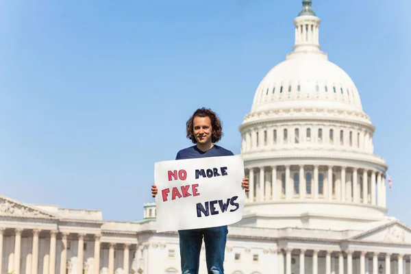 Man protest in front of the USA capitol in Washington holding sign saying no more fake news on social media and newspapers
