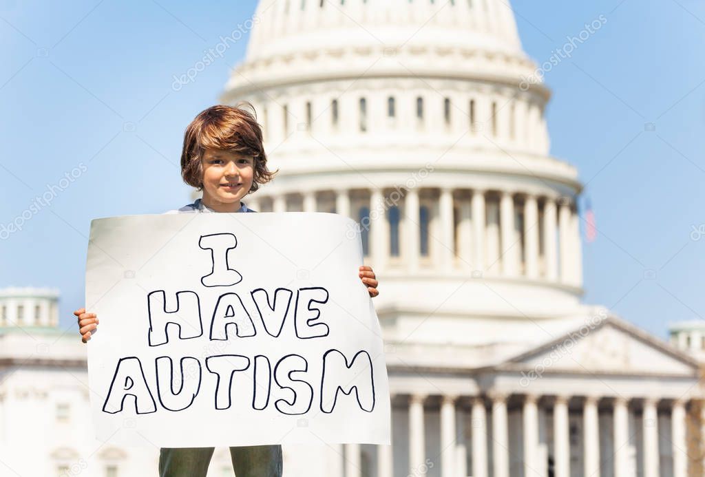 Child boy protest in front of the USA capitol in Washington holding sign saying I have autism