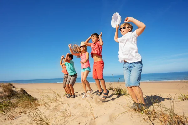 Grupa Szczęśliwych Małych Dzieci Skakać Tańczyć Piaskowej Plaży Wydmy Podnosząc — Zdjęcie stockowe