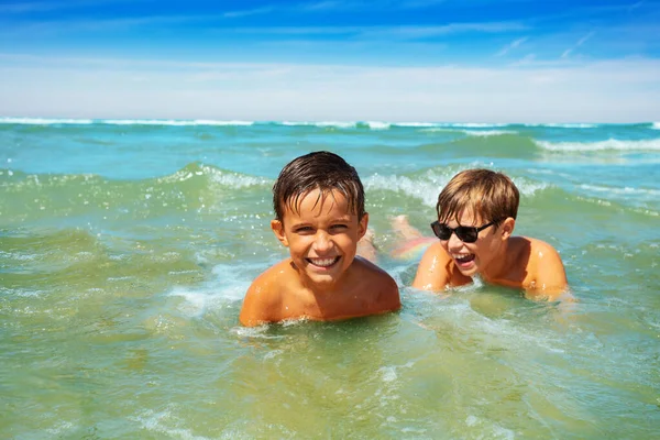 两个快乐的小男孩朋友躺在海浪中享受暑假 — 图库照片