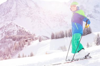 Çocuk kayak portresi, güneşli bir dağ sırasının üzerinde duruyor.