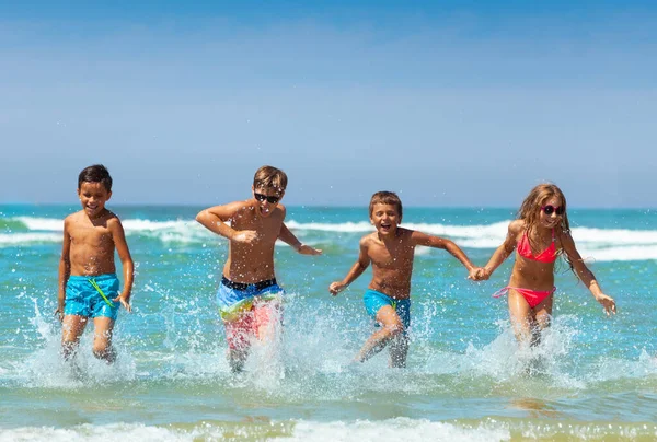 무리의 소녀들 수영복을 튀기고 웃으면서 바다에서 빠르게 달리고 있습니다 — 스톡 사진