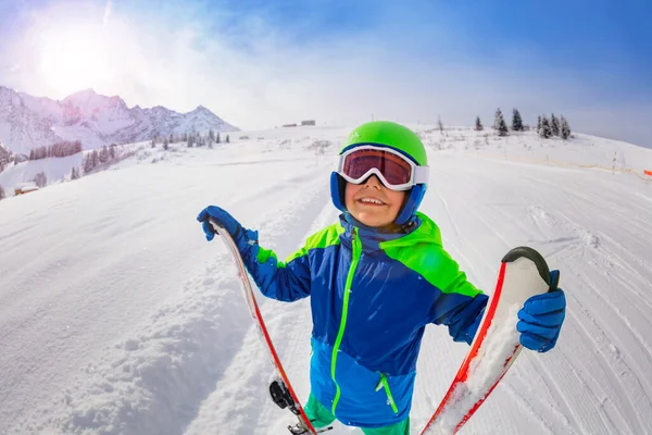 ハッピー小さなスキー少年は 彼のスキーを保持しているマスクを身に着けて笑顔を見上げます新鮮な斜面のスキー — ストック写真