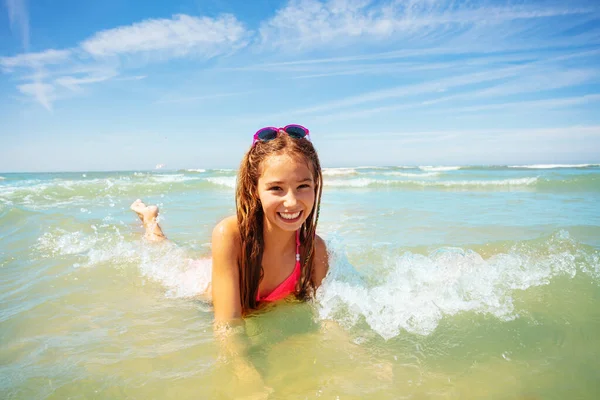 美しい女の子は夏休みに暖かい水を楽しんで海の波に横たわっています — ストック写真