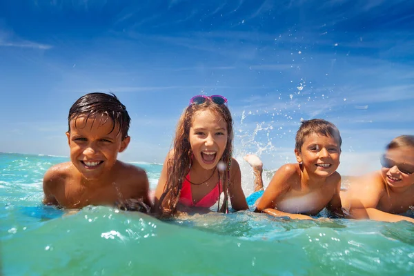 幸せな子供たちのグループ一緒に海の中で水泳ボードの叫び笑って横たわっていた — ストック写真