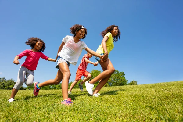 在阳光明媚的天空中 男孩和女孩们牵着手在公园里飞奔 — 图库照片