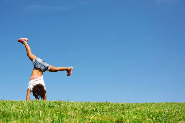 快乐的女孩在草地上漫步 背对着洁白的天空 — 图库照片