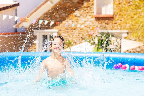 Retrato Chico Divirtiéndose Piscina Haciendo Grandes Salpicaduras Con Casa Fondo — Foto de Stock