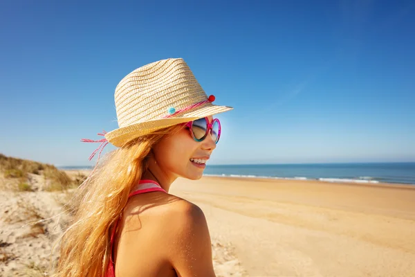 幸せな笑顔ポートレートの女の子でサングラス保持わら帽子オンザビーチサイドプロフィールビュー — ストック写真