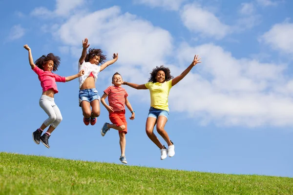 Cuatro Niños Niñas Felices Diversos Saltan Alto Sobre Fondo Del —  Fotos de Stock