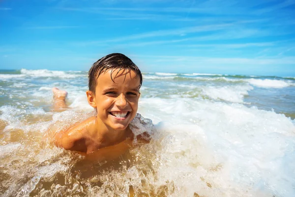 Szczęśliwy Mały Chłopiec Leżał Plaży Falą Wokół Niego Wyrażając Duży — Zdjęcie stockowe