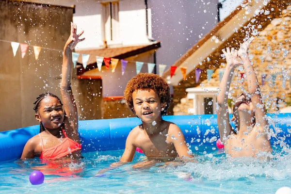 3人の幸せな子供たち男の子と女の子のグループは 暑い夏の日に裏庭のスイミングプールで遊ぶ — ストック写真