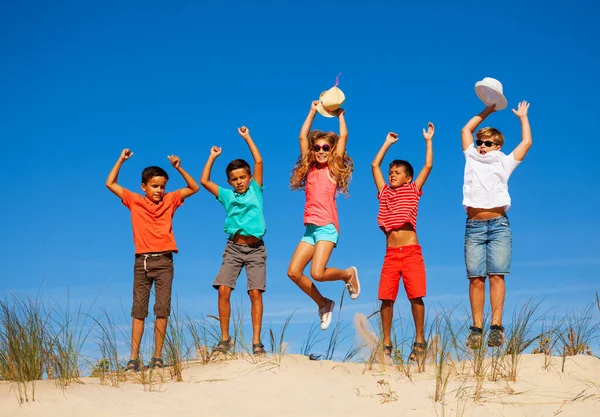 Grupp Barn Hoppa Sanddyn Strand Avslappnade Sommarkläder Över Blå Himmel — Stockfoto