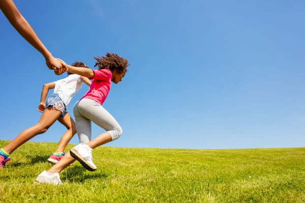 女孩手牵着手在草坪上跑来跑去的侧视图 — 图库照片