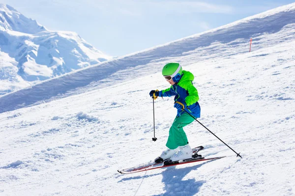 10代の男の子 明るいスポーツウェアと高い山の中で下り坂に乗る衣装で幸せなスキーヤー — ストック写真