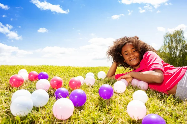 芝生の上でカラフルなボールを遊んで草の中に横たわっている小さな女の子の肖像画 — ストック写真