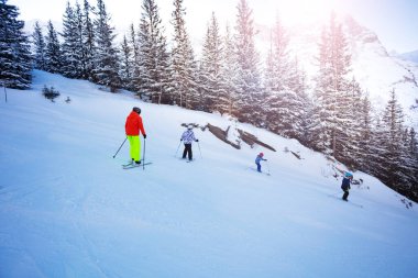 Dağdaki bir grup çocuk okul düzeninde kayak yapıyor.