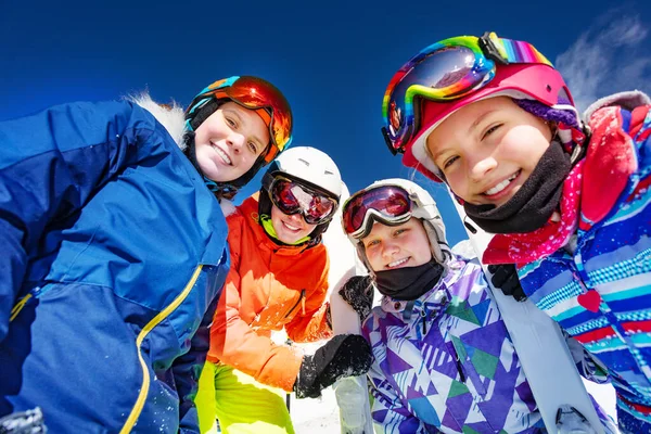 スキー衣装の子供たちのグループマスクAngヘルメットは青い空の上に一緒に立って見下ろす — ストック写真