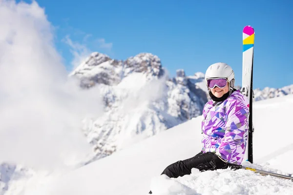 スキー衣装の十代の女の子の肖像画 ヘルメットとマスクは山の上の雪の中でカメラを見て座る — ストック写真