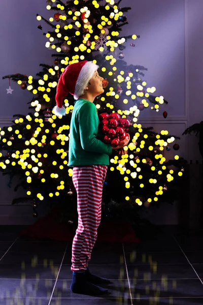 小男孩穿着精灵的节日服装 站在圣诞树旁装饰圣诞树 — 图库照片