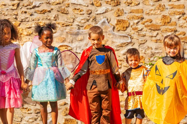 Row Children Halloween Costumes Hold Hands Stone Wall — Stock Photo, Image