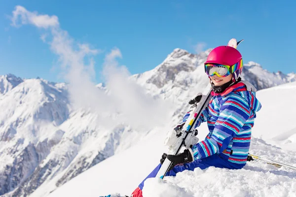 幸せな若い女の子で明るいスポーツ衣装で座っている山の中の雪の山の上に高い山と雲の上に晴れた日に — ストック写真