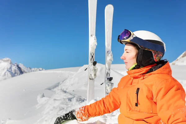 閉じるプロフィール肖像画の十代の女の子でオレンジ明るいスポーツ衣装とともにスキー以上の高い山の峰と青空 — ストック写真