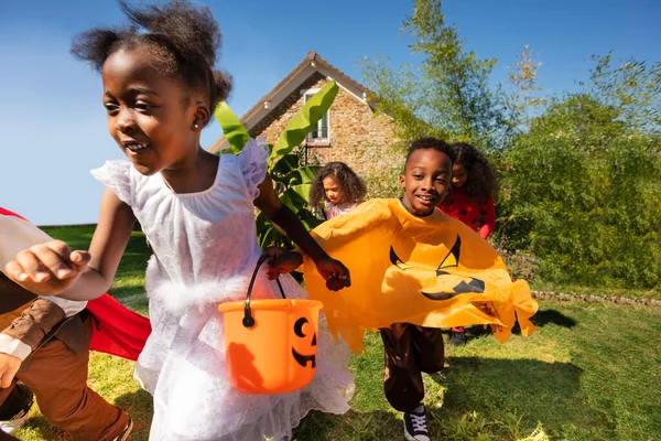 家の手を握る前に芝生の上でハロウィーンの衣装で実行される小さな子供たちのグループの近い肖像画 — ストック写真