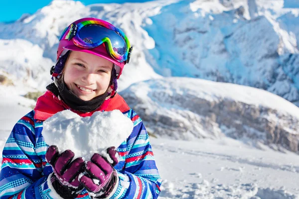 Happy young girl in winter outfit and ski googles, mask hold snow in star shape depicting love mountain vacation concept, close portrait