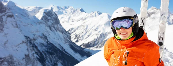 鮮やかなオレンジ色のスポーツ衣装を着た女の子と山のパノラマと空の上のスキーは高山リゾートの雪の中に座っている — ストック写真