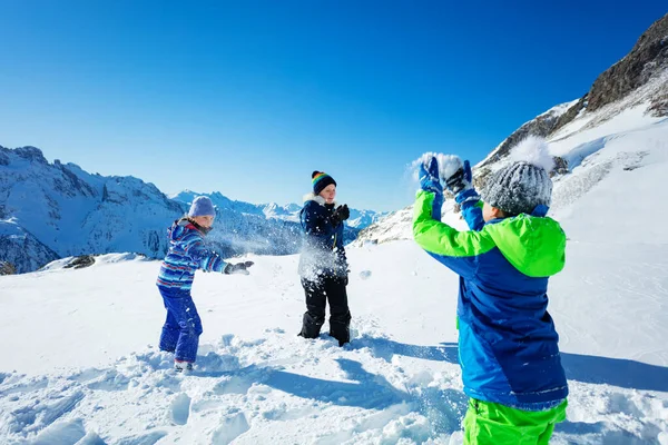 一群孩子在男孩子身后打雪仗 背着雪球 在山上的空中打雪仗 — 图库照片