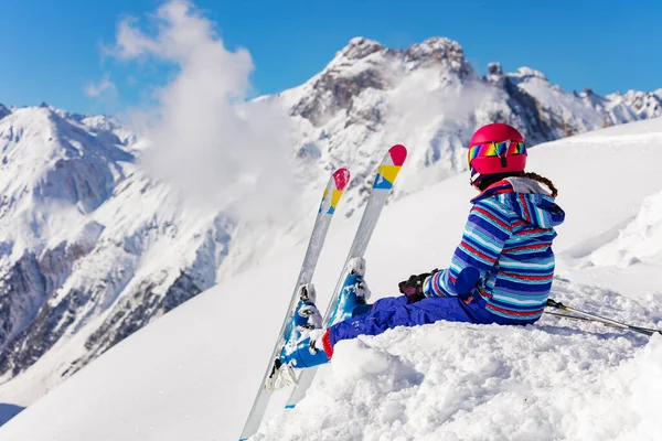 明るいスポーツの衣装を着た幸せな若い女の子が高い山の中の雪の山の上に座っている後ろから谷の景色を見て — ストック写真