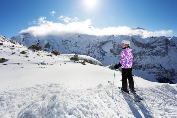 かわいいです幸せな十代の女の子は後ろから冬のスポーツの衣装ビューとスキーの高い山の上に立つ — ストック写真