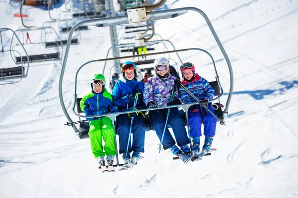 一群滑雪者 孩子们坐在椅子上 坐到山上去滑雪 笑着坐在一起 — 图库照片