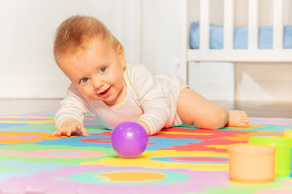 快乐的幼儿在幼儿园的地毯上挂着紫色彩球 — 图库照片