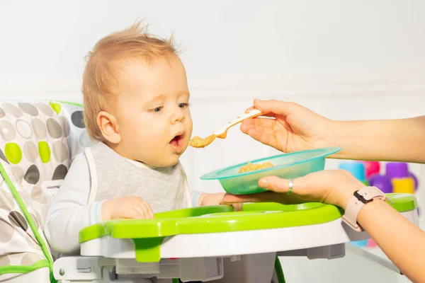 Küçük Çocuk Yüksek Sandalyede Annesinin Önerdiği Kaşıktan Yemek Yemeye Hevesli — Stok fotoğraf