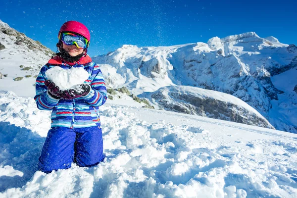 笑顔幸せなかわいい女の子でスキー衣装のマスクとヘルメットショー愛の概念保持雪の形で中心に膝の上に立って山に戻る — ストック写真