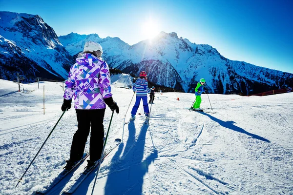 友達と一緒に丘の上でスキーをする子供たちとティーンエイジャーのグループの肖像画 後ろからアルパイン山のリゾートビューで晴れた日 — ストック写真