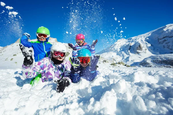 子供たちのグループの肖像画は 地上の美しい山の上に空気中の雪を投げるに横たわっていた — ストック写真