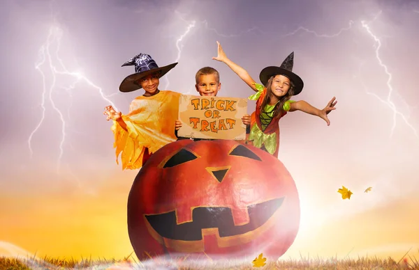 Kindergruppe Mit Leckerli Schild Sitzt Auf Riesigem Halloween Gruselkürbis Über — Stockfoto
