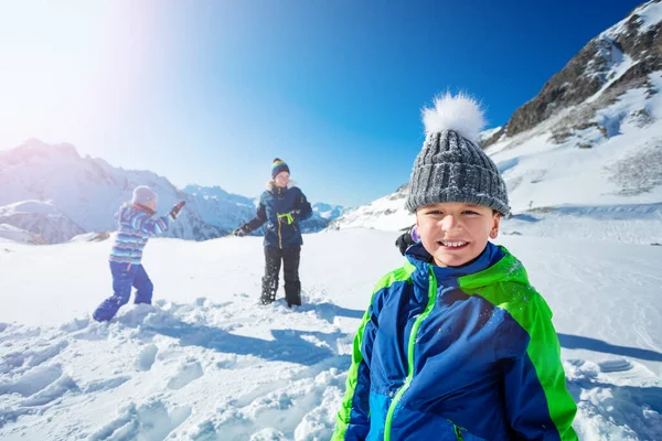 女の子と冬の山の中で男の子の肖像は バックグラウンドで雪合戦を再生します — ストック写真