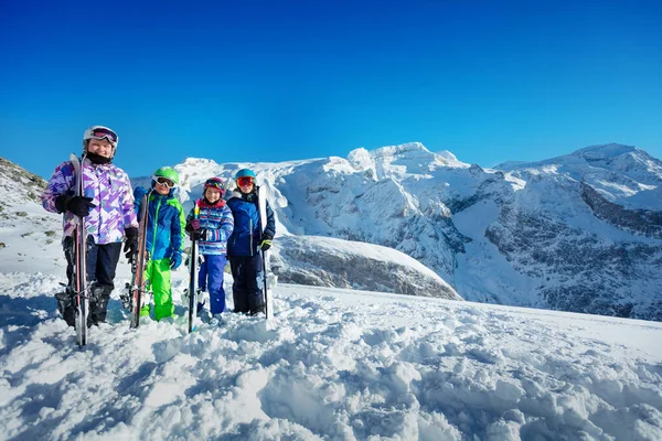 スキースクールグループの肖像画 子供たちは笑顔の背後に山のピークと雪を保持スキーに立つマスクをオフにしている — ストック写真